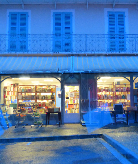 image de la bouquinerie éclairée de l'interieur, avec des tons bleutés